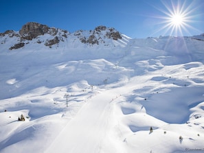 Eine verschneite Berglandschaft mit Seilbahnen und blauem Himmel.