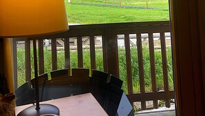 A room with a view of a mountainous landscape, a wooden table, and a lamp. - Balcons B 011 - Parc Nat. Vanoise Appart. 6 Pers (Val-Cenis)