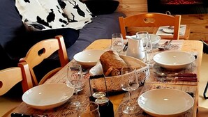 A dining area with a wooden table set for four, surrounded by chairs. A fireplace is visible in the background. - Balcons B 011 - Parc Nat. Vanoise Appart. 6 Pers (Val-Cenis)