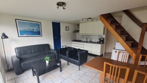A compact living space with a sofa, a coffee table, a dining table with chairs, a kitchen area, and a staircase. - Bungalowpark Simpelveld - Delta 109 (Simpelveld)