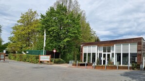 Een modern gebouw met grote ramen, een naambord en een verbodsgebaar.