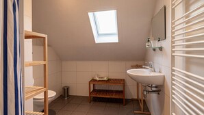 A small, modern bathroom with a skylight, a toilet, a sink, and a shower area. - Bungalowpark Simpelveld - Delta 148 (Simpelveld)