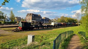 A train station with a stationary train on the tracks, surrounded by greenery and buildings. - Bungalowpark Simpelveld - Delta 148 (Simpelveld)