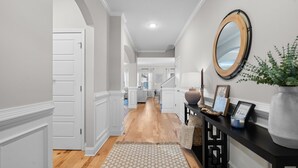 A hallway with a wooden floor, white walls, a black console table with decorative items, and a large mirror on the wall. - Charming 4-bedroom house with WiFi, AC in wonderful North Augusta (North Augusta)