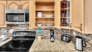 A kitchen with wooden cabinets, a stainless steel microwave, a stove, a coffee maker, and a toaster.
