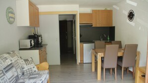 Een knus woongedeelte met een kitchenette, een eethoek en een bank.