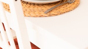 Una mesa de comedor dispuesta con platos blancos, vasos transparentes y posavasos tejidos.