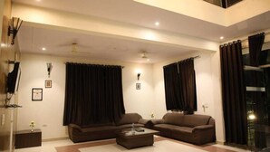 A modern living room with two sofas, a coffee table, and a ceiling fan. - Hotel Grand Ranthambore (Sawai Madhopur)