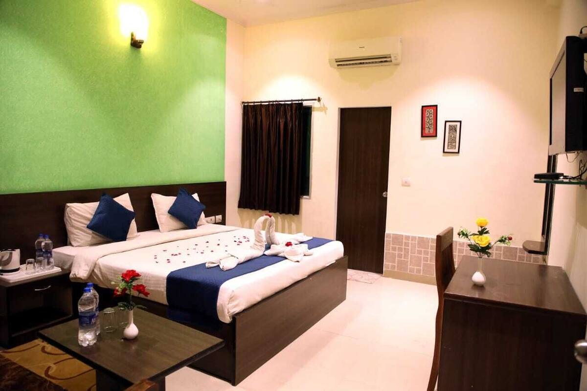 A hotel room with a bed, bedside table, and a small desk with a chair.
