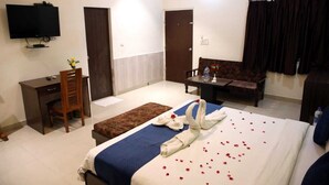 A hotel room with a bed, a desk, a chair, a TV, and a sofa. - Hotel Grand Ranthambore (Sawai Madhopur)
