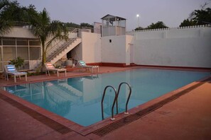 A swimming pool with a covered area, stairs, and lounge chairs. - Hotel Grand Ranthambore (Sawai Madhopur)