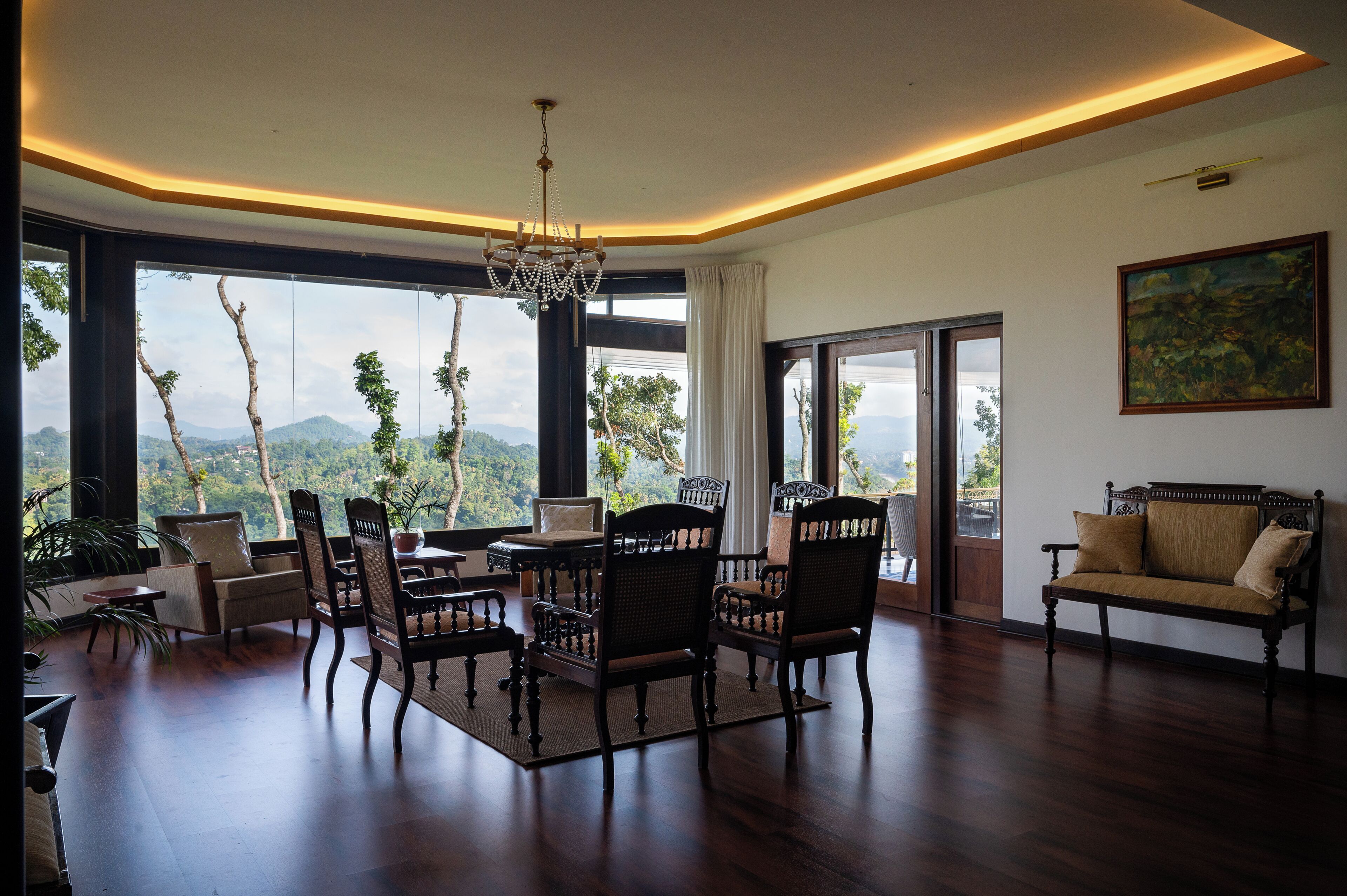 En rummelig stue med spiseplads, en sofa og et stort vindue med udsigt til bjergene.