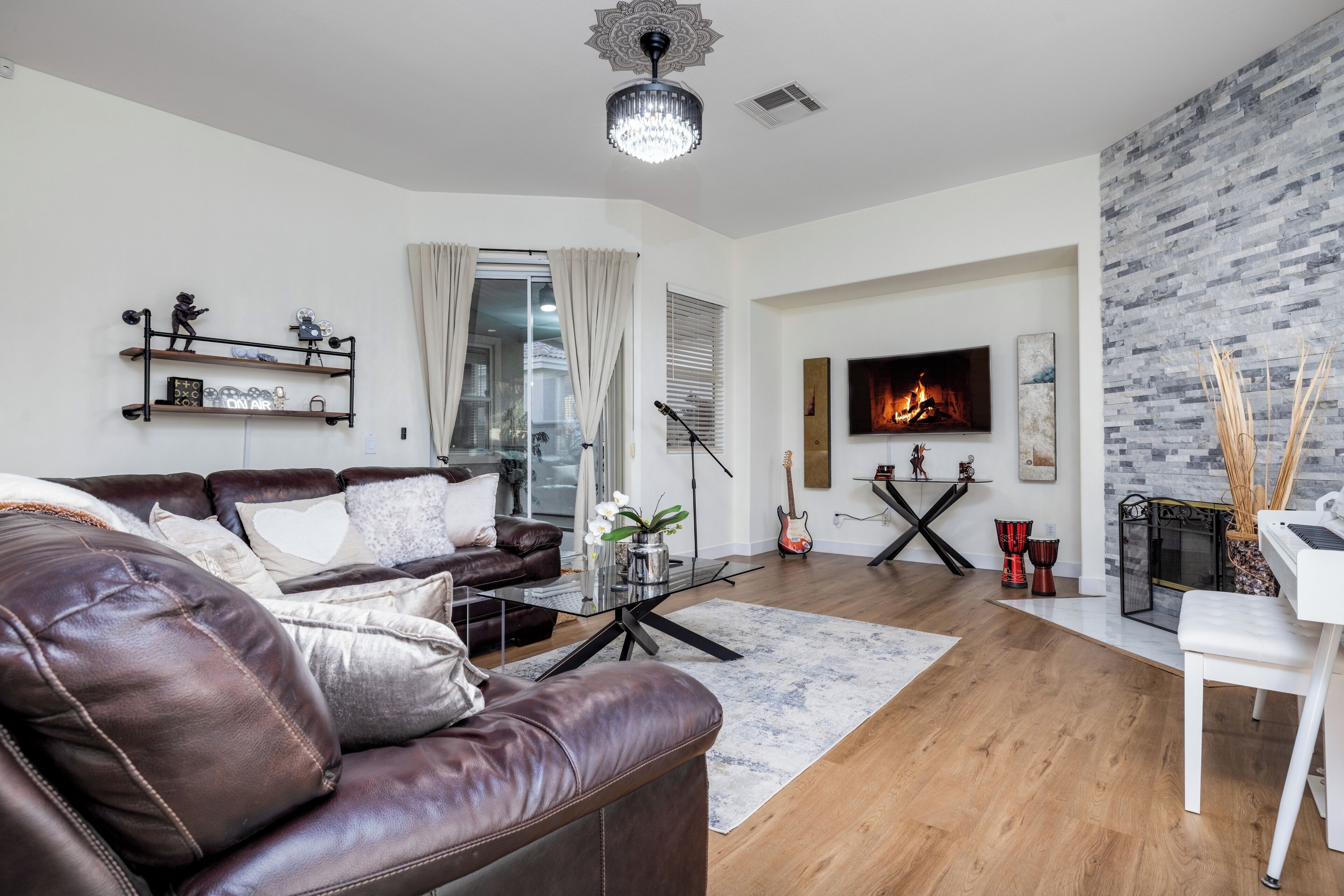 A modern living room with a leather sofa, a coffee table, a fireplace, and a TV.
