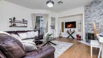 A modern living room with a leather sofa, a coffee table, a fireplace, and a TV.