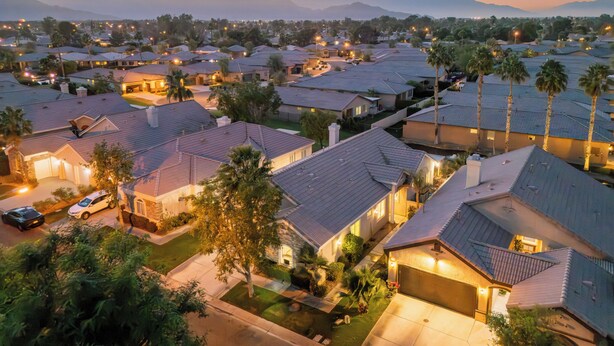 A residential area with houses featuring sloped roofs and well-maintained lawns.