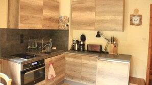 Une cuisine compacte avec des meubles en bois, un four encastré et une machine à café.