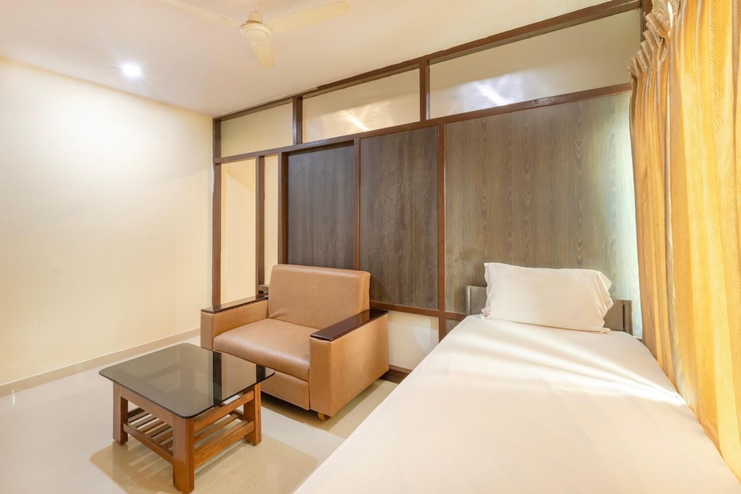 Une chambre d’hôtel avec un lit, un canapé, une petite table et un ventilateur de plafond.