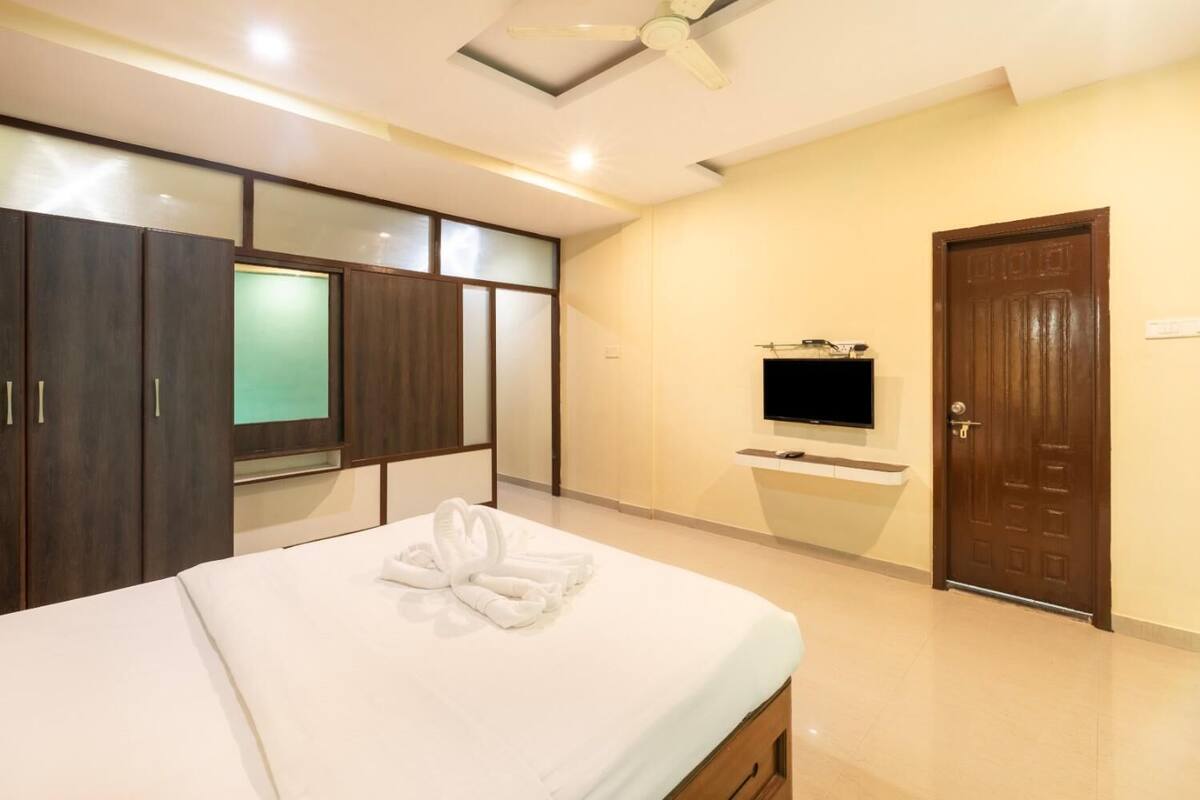 A hotel room with a bed, a TV, a wardrobe, and a door.