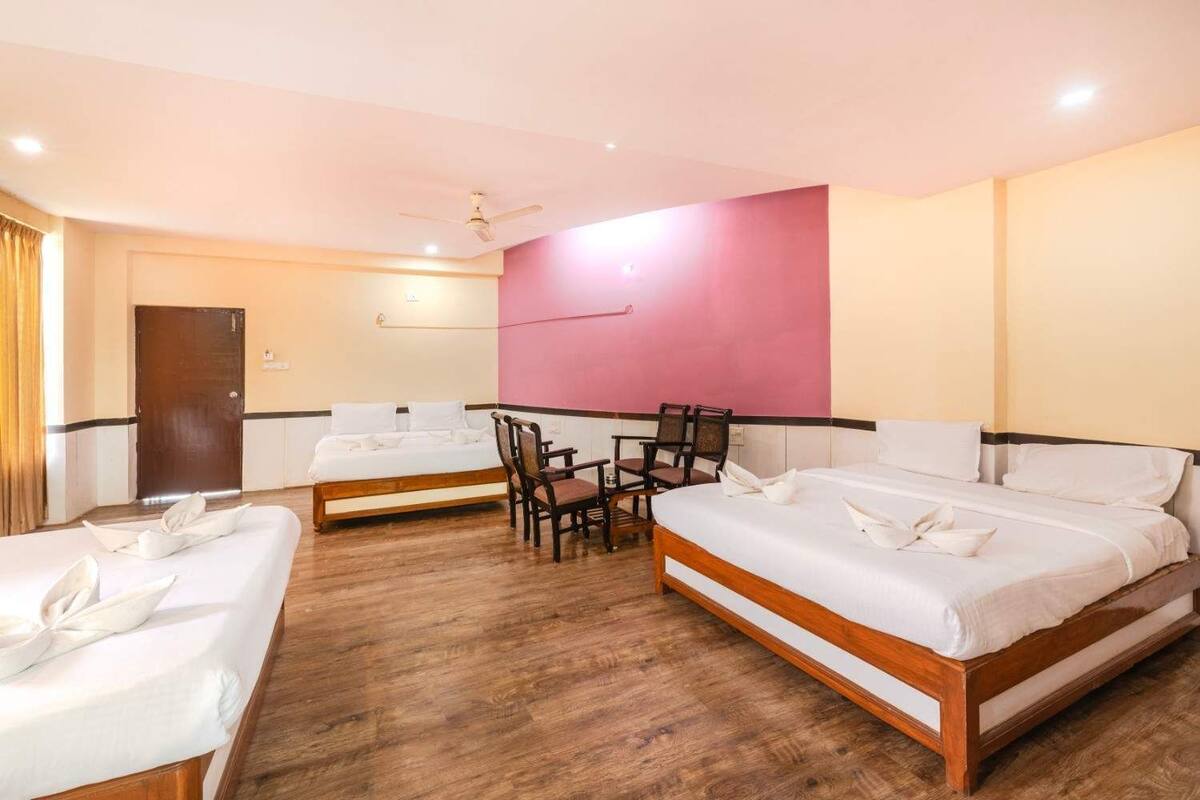 A hotel room with two beds, a wooden floor, a desk, and a chair.
