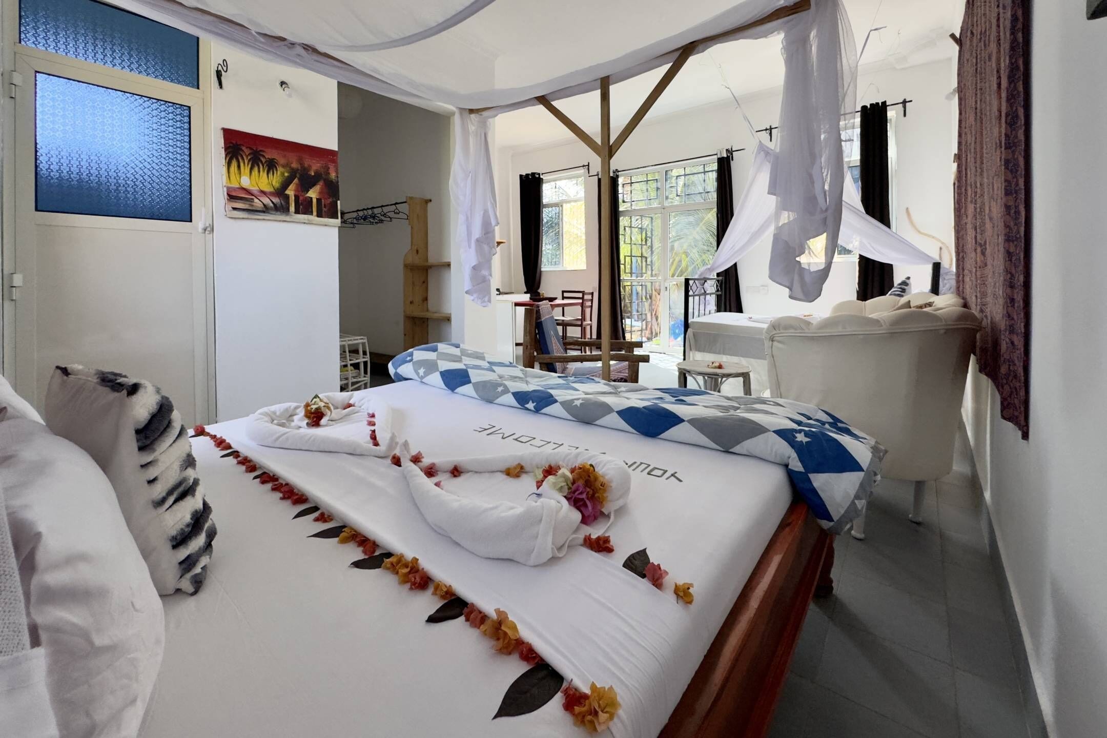 A hotel room with a bed, a desk, and a chair. There is a window with curtains and a view of the outside.