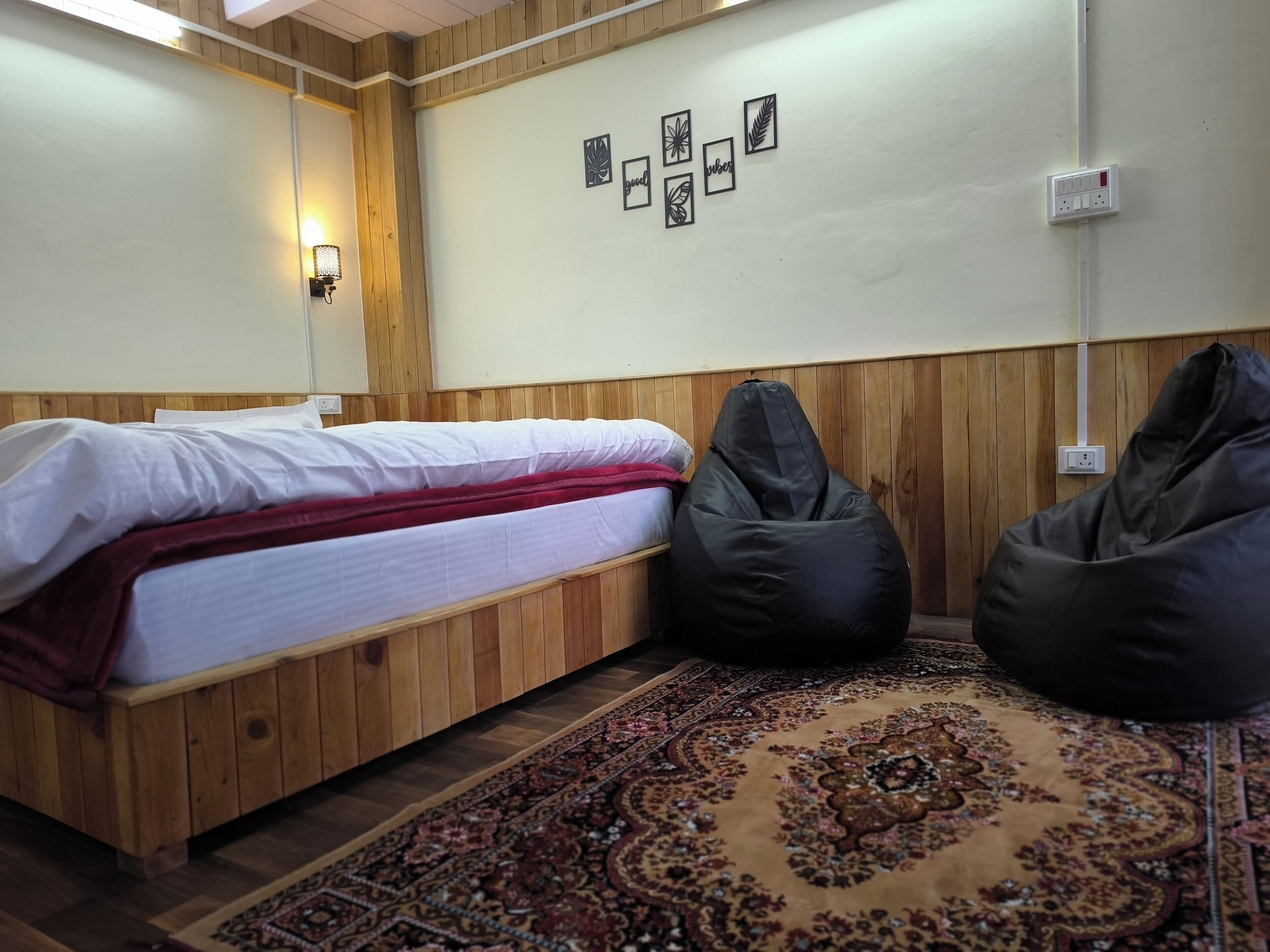 A room with a wooden bed, a patterned rug, and a wall with framed artwork.
