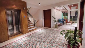 A hotel lobby with a patterned floor, a staircase, and a reception area. - The Angel Hotel And Suites (Gurugram)
