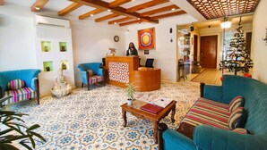 A hotel lobby with a reception desk, blue sofas, patterned floor tiles, and a Christmas tree. - The Angel Hotel And Suites (Gurugram)