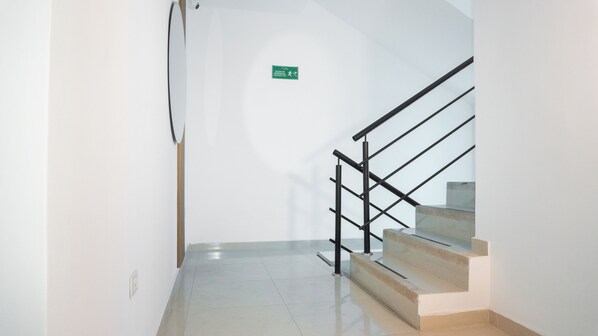A staircase with a handrail and a green emergency exit sign on the wall. - FR Dreams Hotels (Santa Marta)