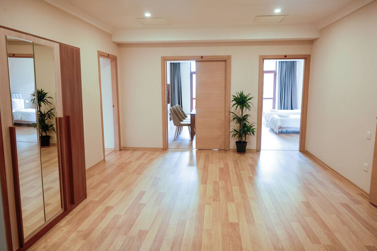 Une chambre d’hôtel avec un plancher en bois, un lit, un bureau et deux plantes en pot.