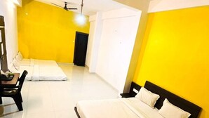 Una habitación con dos camas, un ventilador de techo y una puerta blanca.
