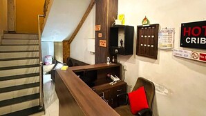 Un vestíbulo de hotel con mostrador de recepción, una escalera y un ventilador de techo.
