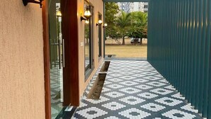 A corridor with patterned tile flooring, a metal roof, and wall-mounted lights. - Vrindavan Greens Resort (Udaipur)