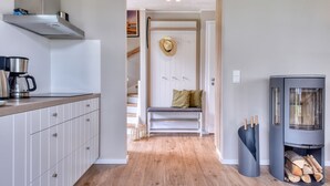 Eine moderne Küche mit Kaffeemaschine, einer Bank mit Kissen, einem Kamin und Holzboden.