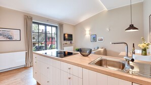 A modern kitchen with a large island, stainless steel sink, and pendant lighting. - Newly built, modern, exclusive - that describes the Klein Stresow vacation village (Klein Stresow)