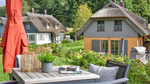 A wooden table with wicker baskets, a potted plant, and books. - Newly built, modern, exclusive - that describes the Klein Stresow vacation village (Klein Stresow)
