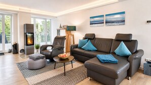 Een moderne woonkamer met een open haard, een leren bank en een groot raam.