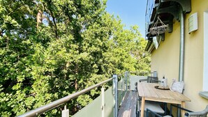 Una terraza de madera con una mesa y sillas, con vistas a una zona verde exuberante con árboles.