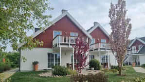 Una casa a due piani con tetto rosso e pareti bianche, con un balcone al piano superiore.