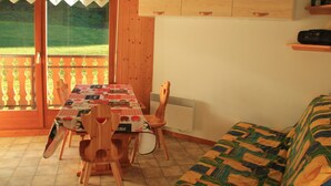 Une pièce comprenant une table à manger, des chaises, un canapé et une fenêtre donnant sur un paysage verdoyant.