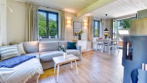 A modern living room with a sofa, a coffee table, and a dining area with chairs and a table. - Newly built, modern, exclusive - that describes the Klein Stresow vacation village (Klein Stresow)