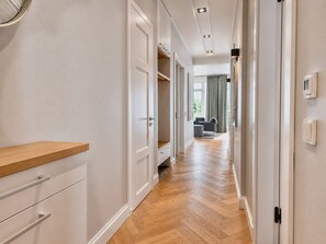 A hallway with wooden flooring, white walls, and a wooden counter on the left.