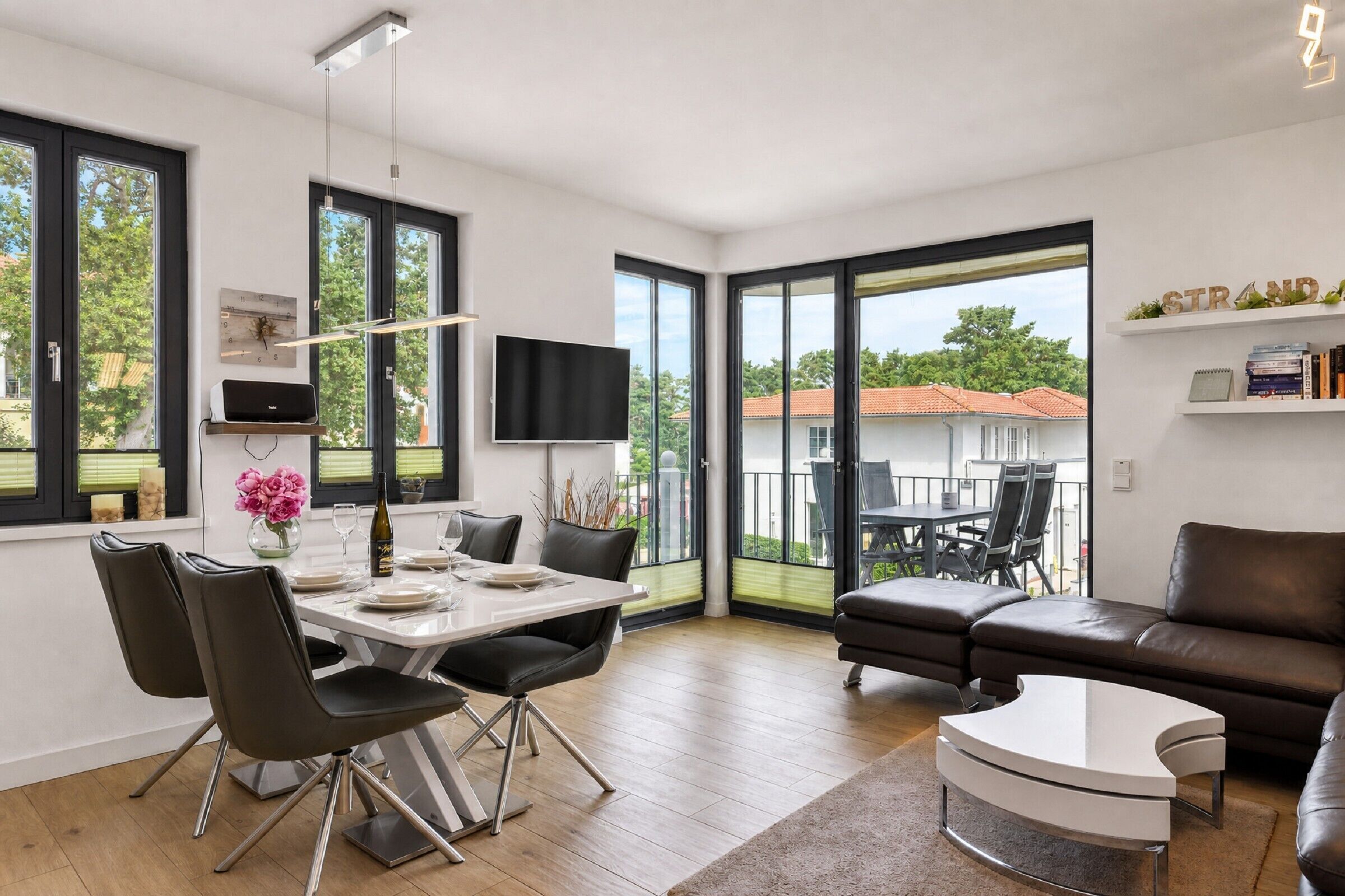 A modern living space with a dining area, a sofa, and a TV.
