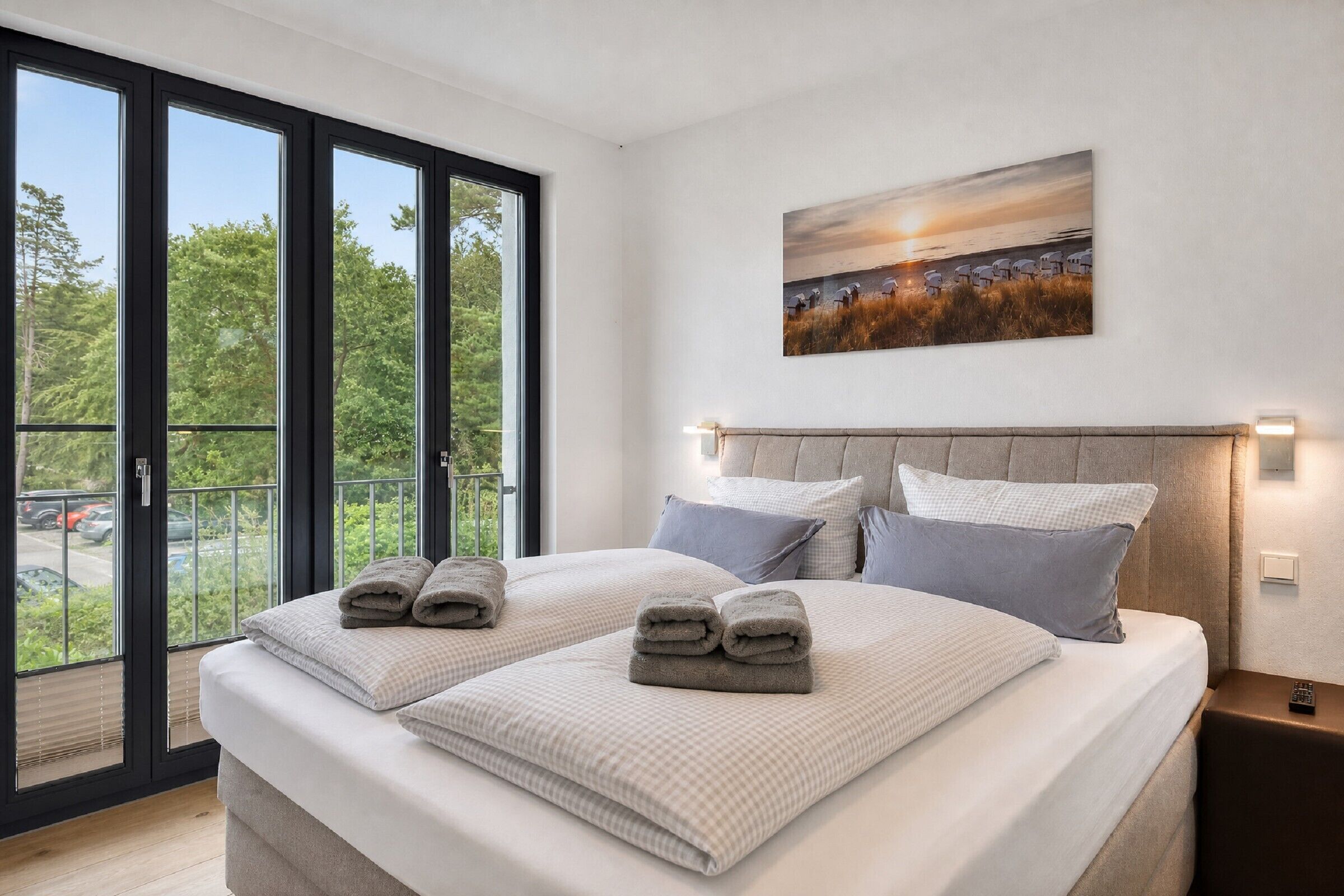 Une chambre d’hôtel avec un grand lit, deux oreillers, une tête de lit, un tableau et une vue par la fenêtre.