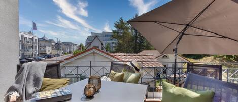 A balcony with a table, chairs, and an umbrella.