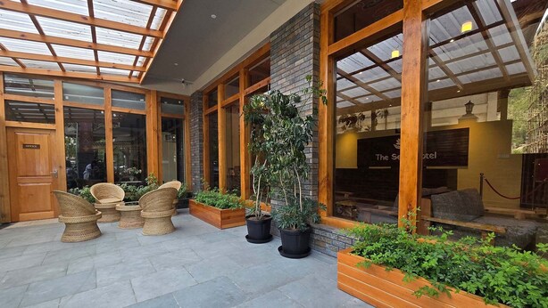 Un hall de hotel con techo de cristal, mobiliario de mimbre y plantas en macetas.