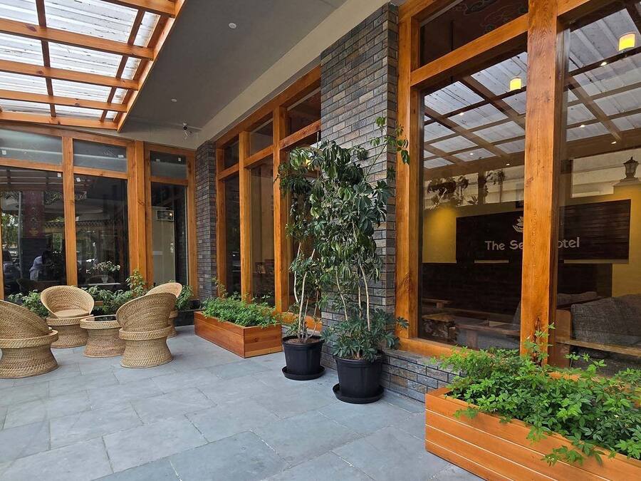 Un hall de hotel con techo de cristal, mobiliario de mimbre y plantas en macetas.