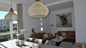 Uma sala de estar moderna com um sofá marrom, uma mesa de jantar com flores brancas e uma janela grande com cortinas.
