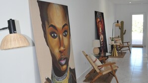 Um quarto espaçoso com piso de mármore, um quadro grande na parede e um espaço de estar com cadeiras e uma mesa pequena.