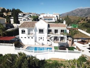 A large white building with multiple balconies and a swimming pool.