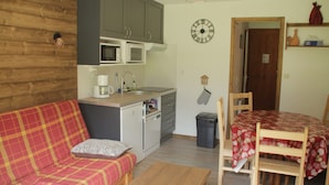 A compact living space with a kitchenette, a sofa, a dining table, and a wooden floor. - Christina CR8 Family & Mountain 6 Pers (Chatel)
